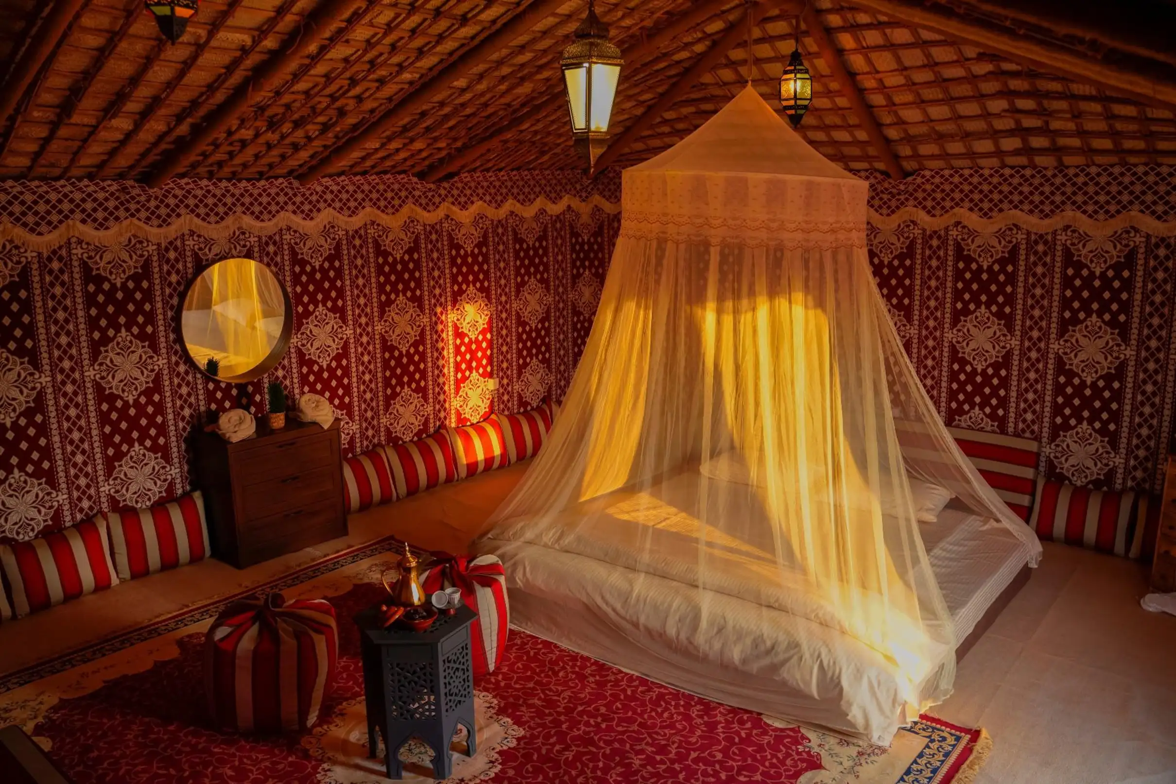 Ornate bedroom inside a traditional Arabian desert tent with golden light