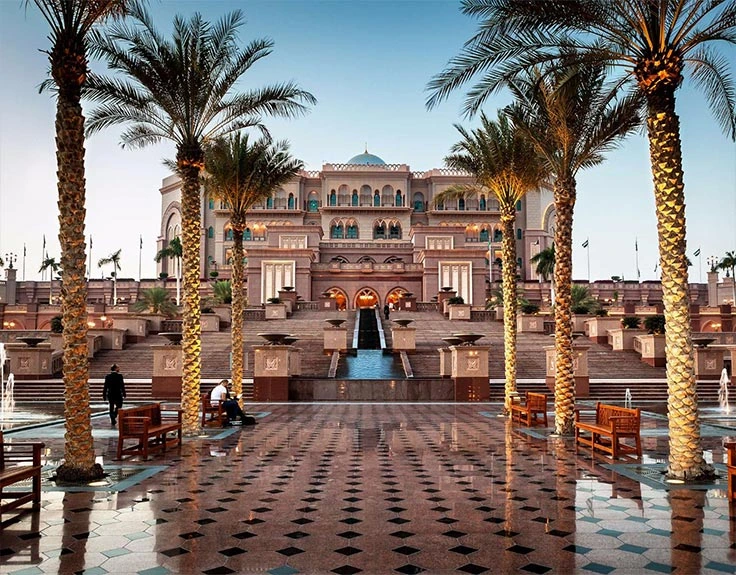 Emirates Palace grand building entrance with fountains and multiple palm trees