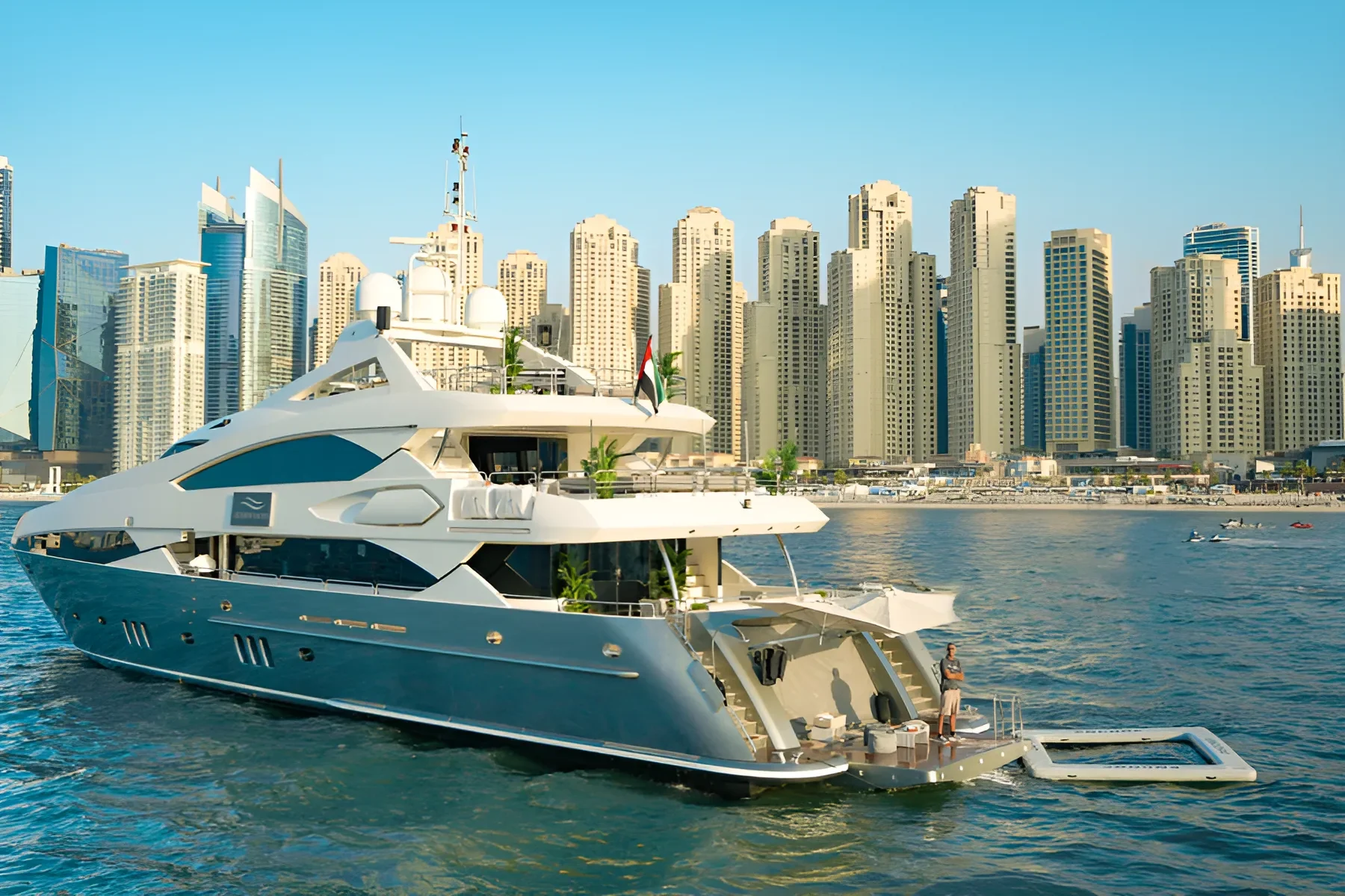 Luxury yacht sailing past Dubai cityscape on clear blue water