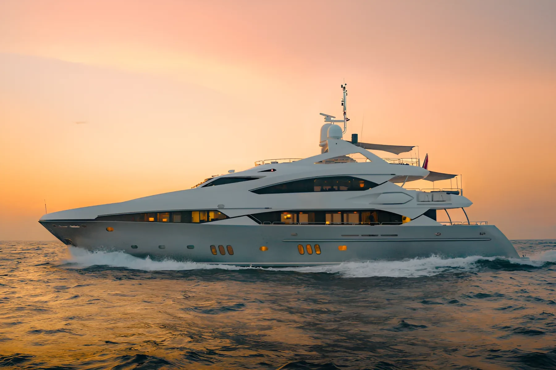 Luxury yacht sailing at sunset, creating a wake in the water