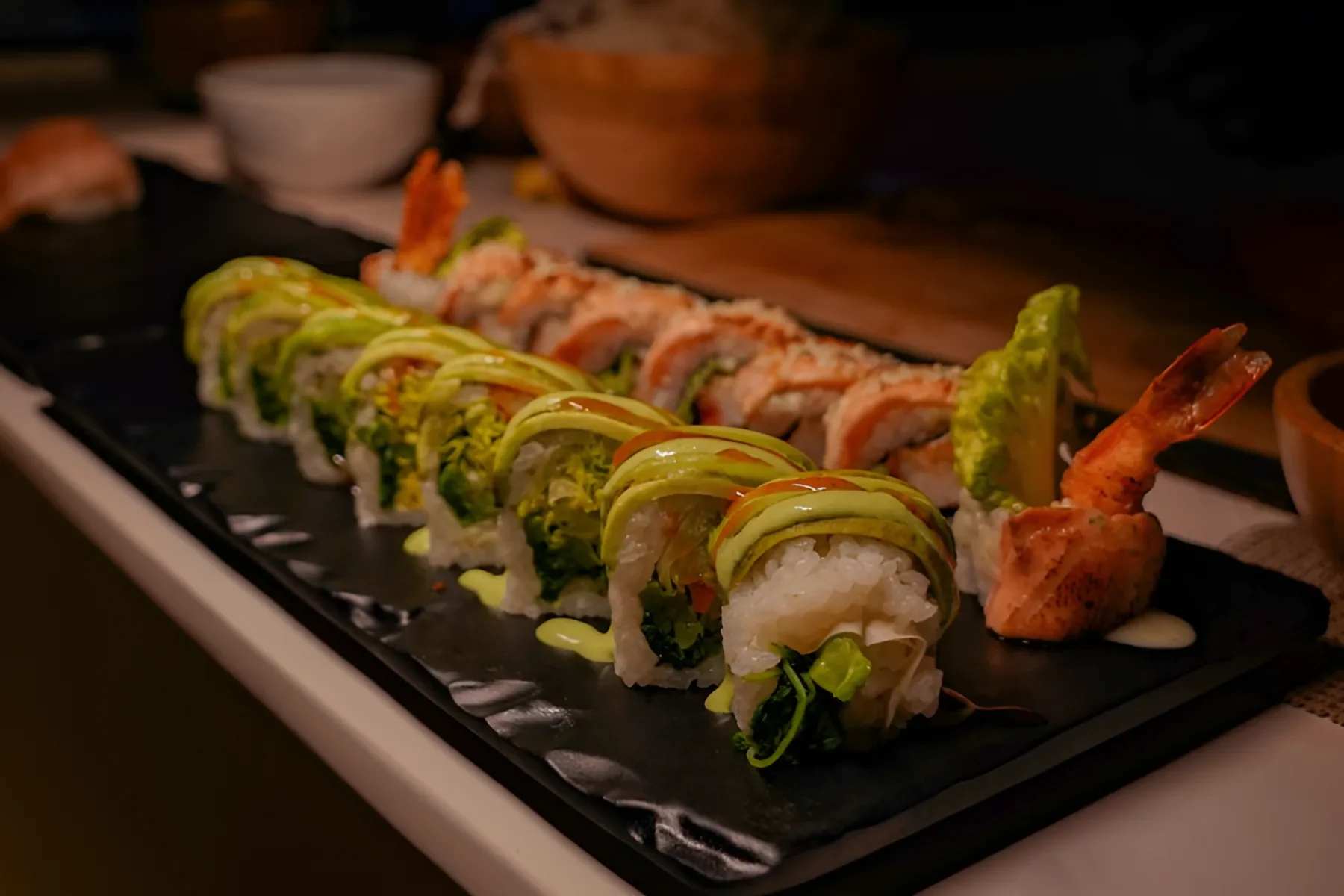 Platter of avocado, vegetable, and shrimp sushi rolls with sauces